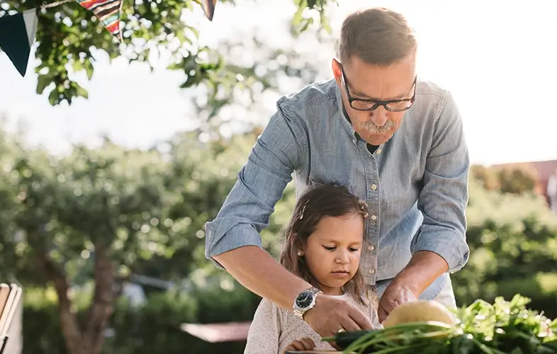 A grandfather gardening with his granddaughter