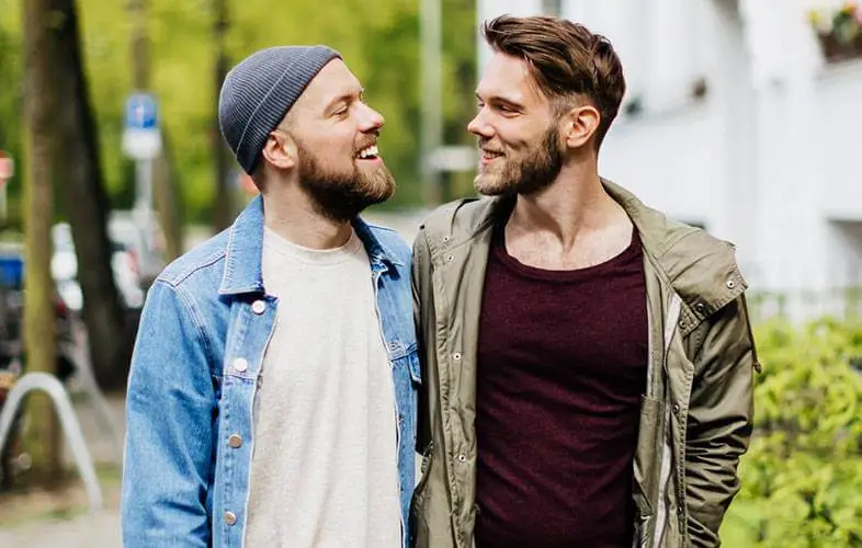 A happy couple walking on a sidewalk.