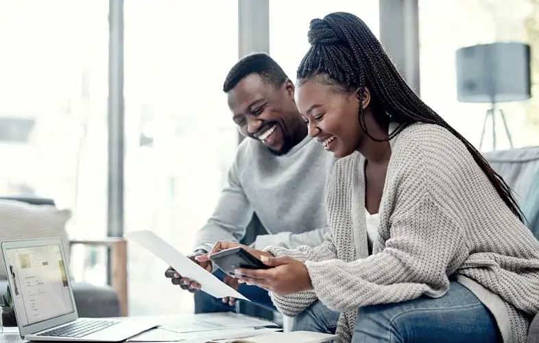 A man and woman working at a computer and looking over documents