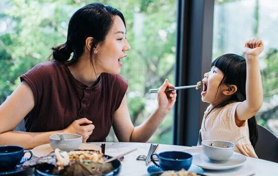 A mother feeding her child at a restaurant